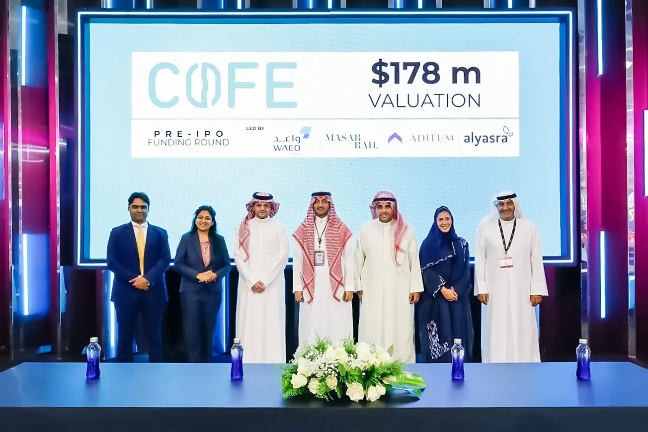 Group of professionals at a funding announcement event, with a screen displaying